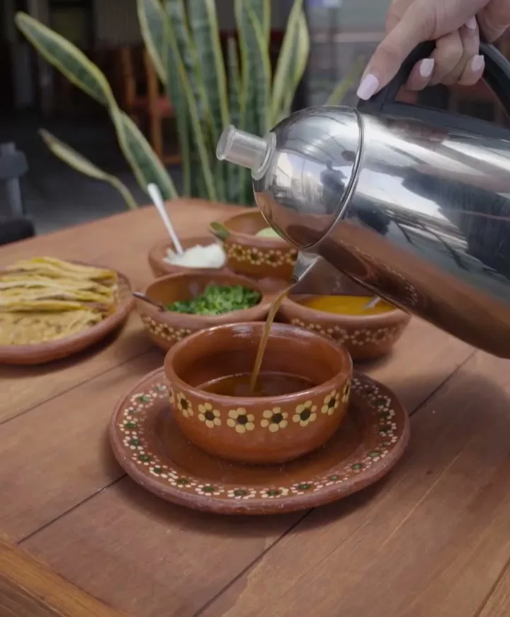 La coctelera sirviendo sobre la mesa, con las salsas en cazuelitas de barro.