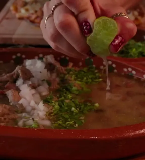 Carne en su jugo servida en cazuela de barro, con cilantro y cebolla encima.